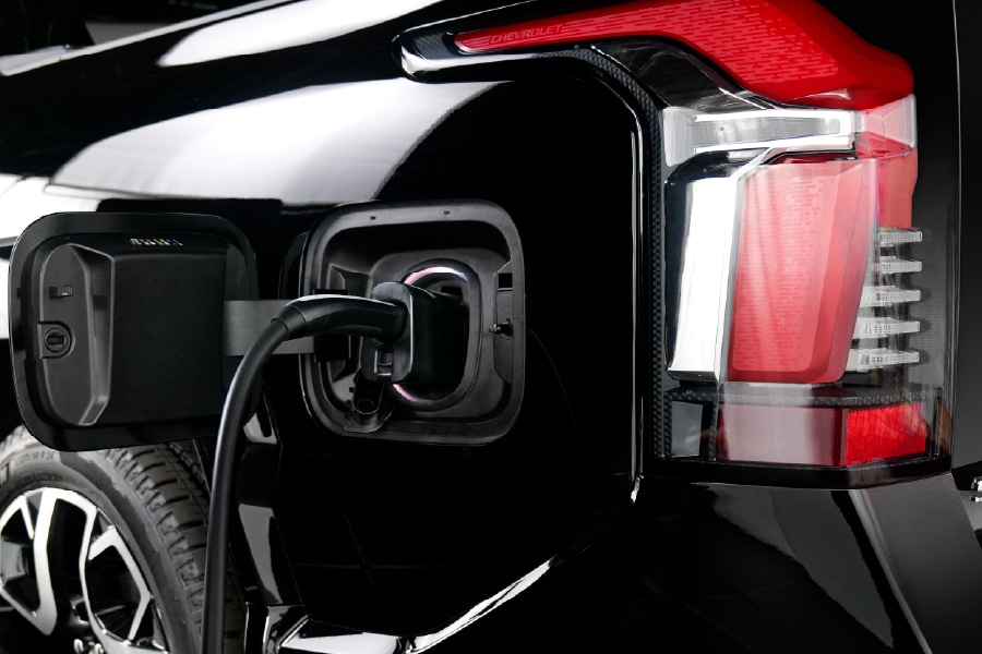 Electric vehicle charging at a station, showing rear light and charging cable.
