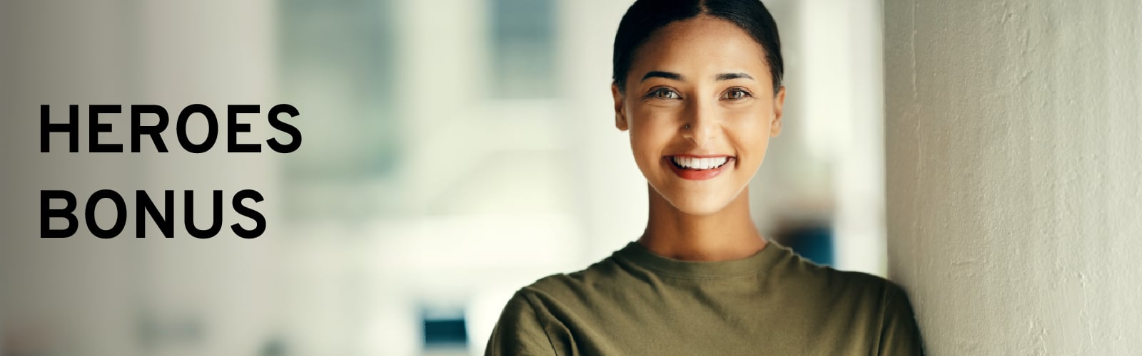 Smiling person standing near a wall with "HEROES BONUS" text beside them.