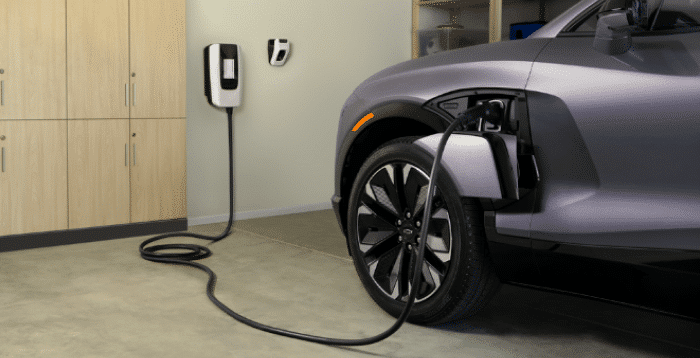 Electric vehicle charging in a garage with wall-mounted charger and modern cabinets.
