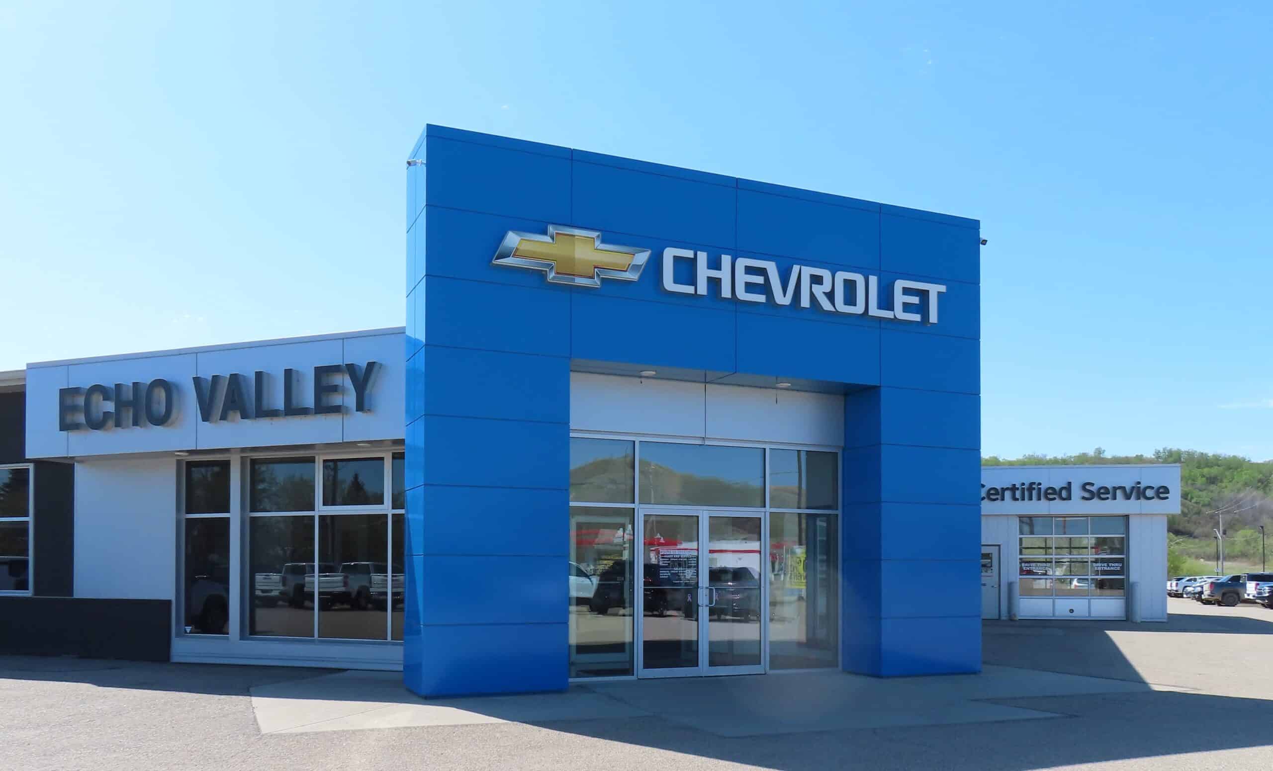 Chevrolet dealership with blue exterior, Echo Valley sign, and Certified Service area under a clear sky.