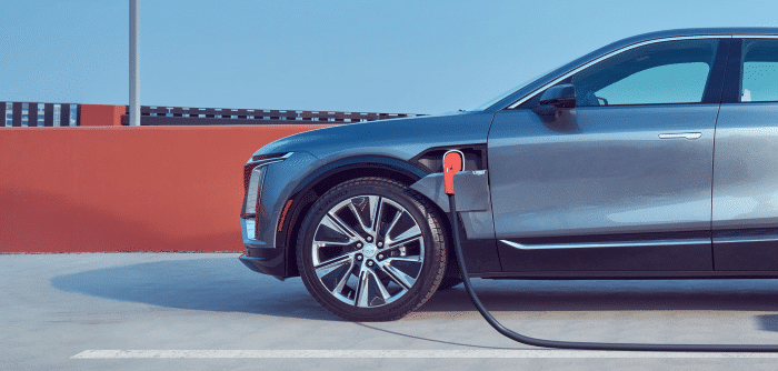 Electric car charging at a station with blue sky background.